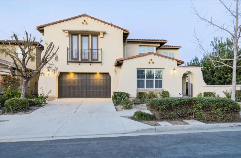 Two story home exterior with shutters, gable roof and landscaping