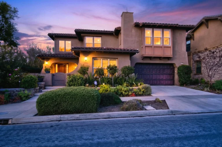 Mediterranean exterior at twilight with stucco walls, arches and red tile roof